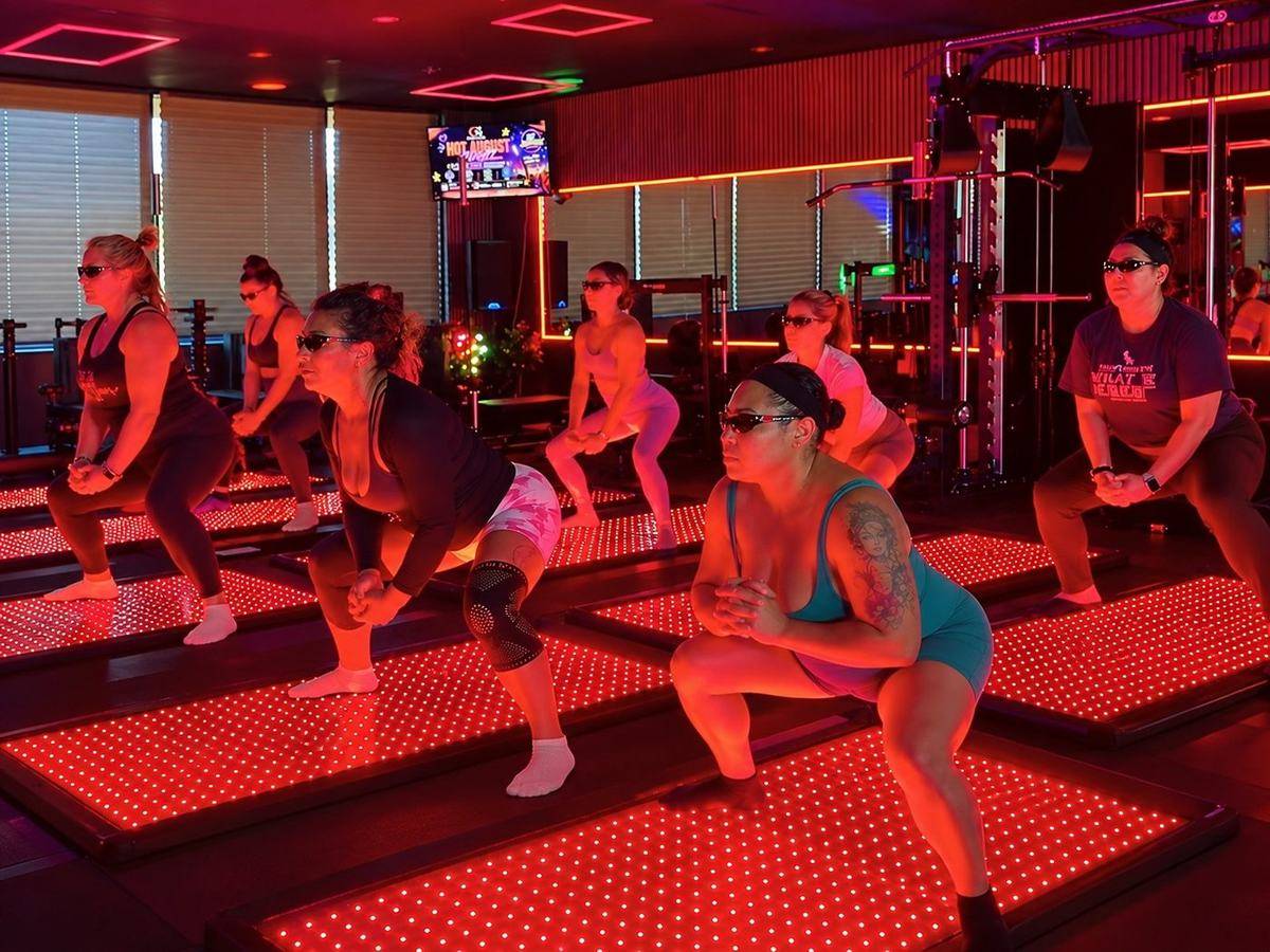 Women squatting on glowing infrared mats in a Signature Bolates mat Pilates class